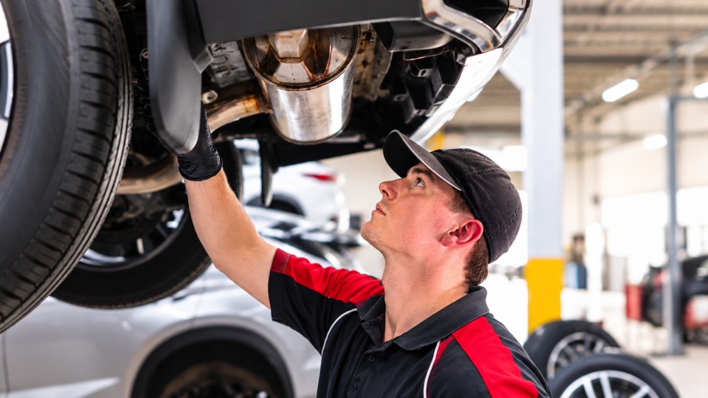 Mechanic inspecting exhaust under a raised vehicle at Newcastle Automotive Services